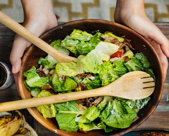 Two hands hold up a bowl of salad